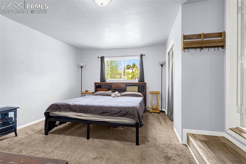 Image 14 of 30: Carpeted bedroom featuring a textured ceiling and baseboards