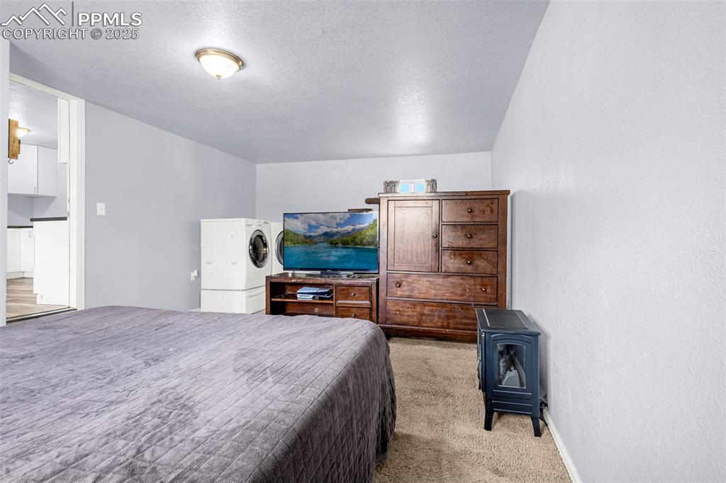 Image 15 of 30: Bedroom featuring washer / clothes dryer, light carpet, and a textured ceil