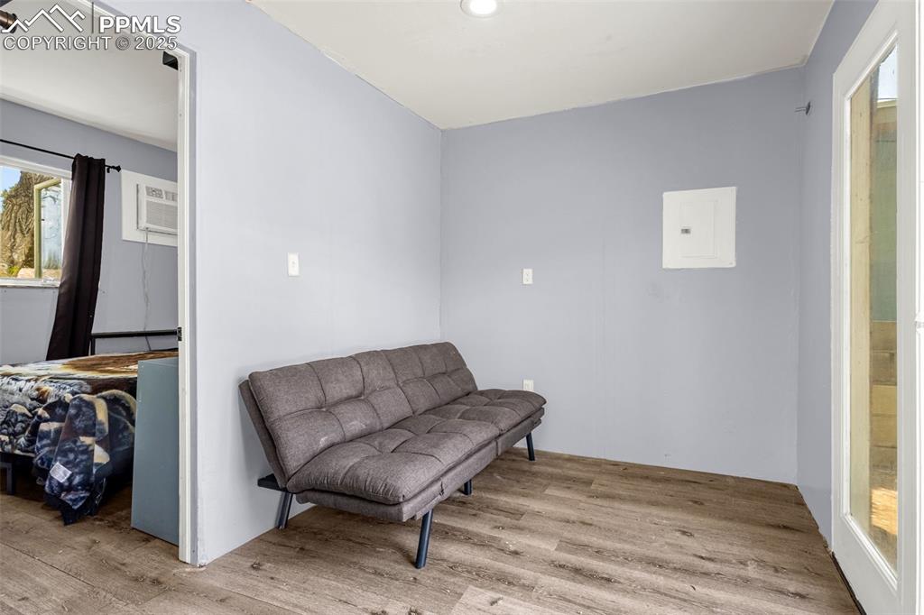 Image 17 of 30: Living area with wood finished floors, a wall mounted AC, recessed lighting
