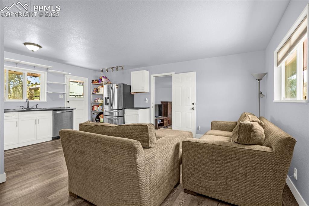 Image 4 of 30: Living area featuring wet bar, dark wood-type flooring, and a textured ceil