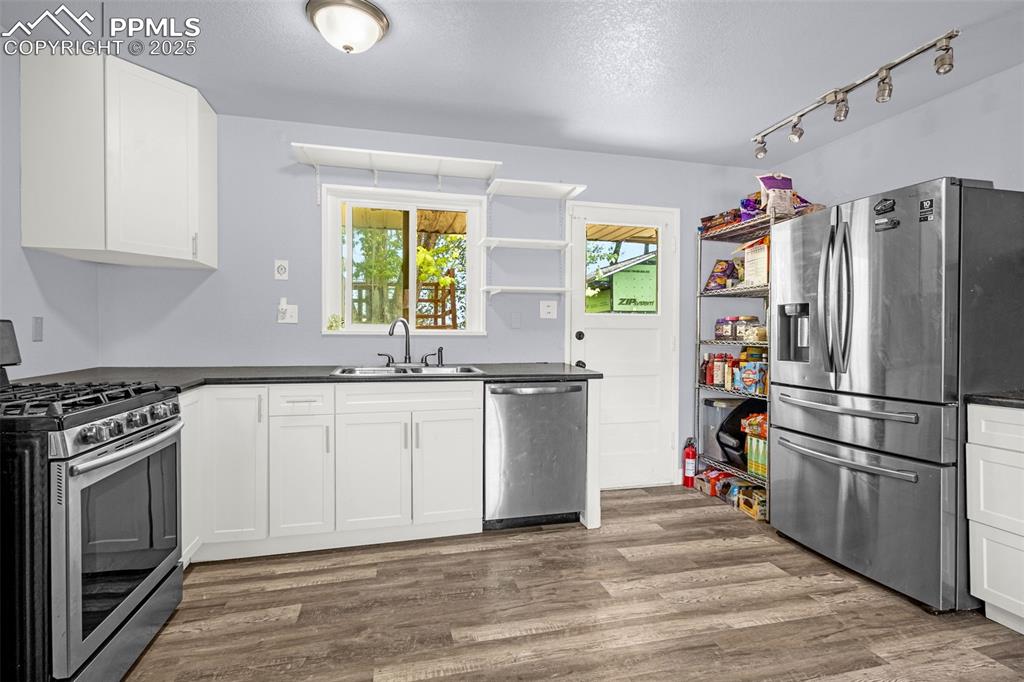 Image 6 of 30: Kitchen with stainless steel appliances, a sink, open shelves, dark counter