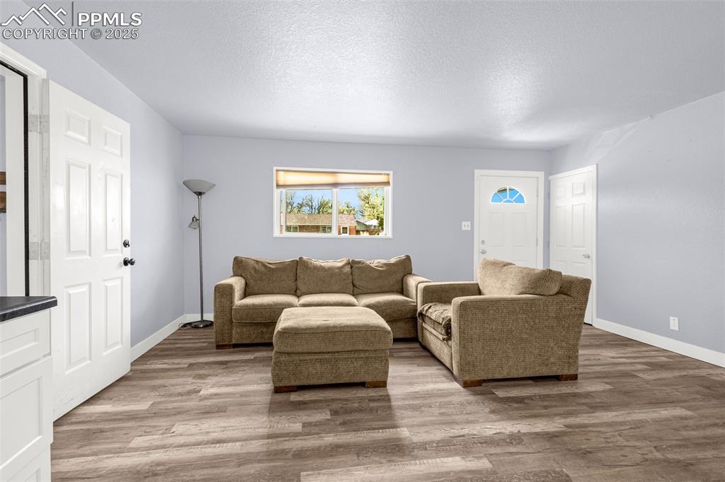 Image 7 of 30: Living area with wood finished floors, baseboards, and a textured ceiling