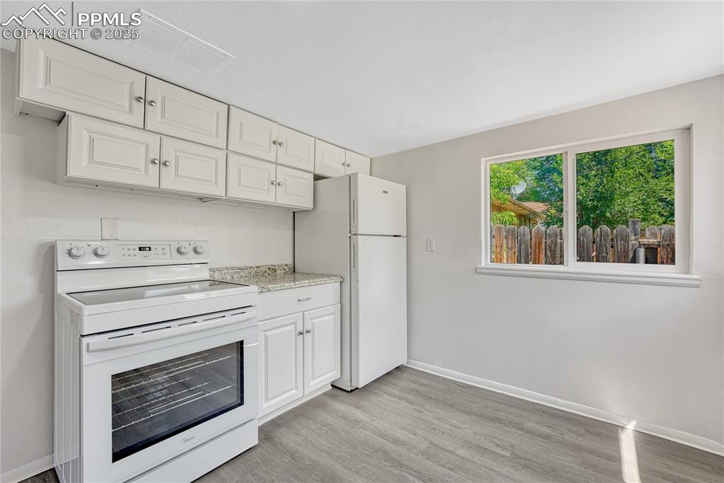 Image 11 of 29: Kitchen featuring white appliances, light wood-style floors, and white cabi