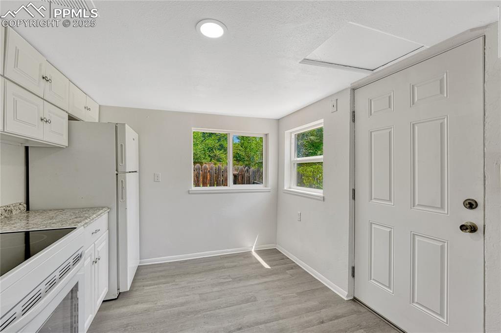 Image 12 of 29: Kitchen featuring light wood-style floors, white cabinetry, and white appli