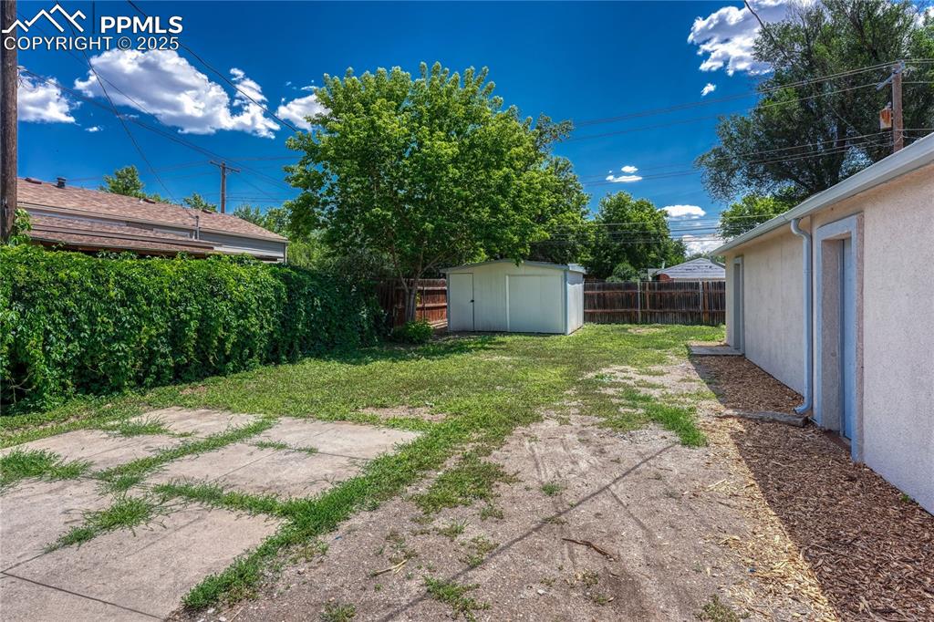 Image 27 of 29: Fenced backyard featuring a storage unit and a patio