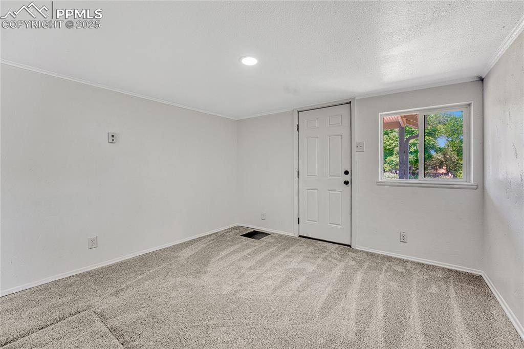 Image 4 of 29: Spare room with carpet, a textured ceiling, and ornamental molding