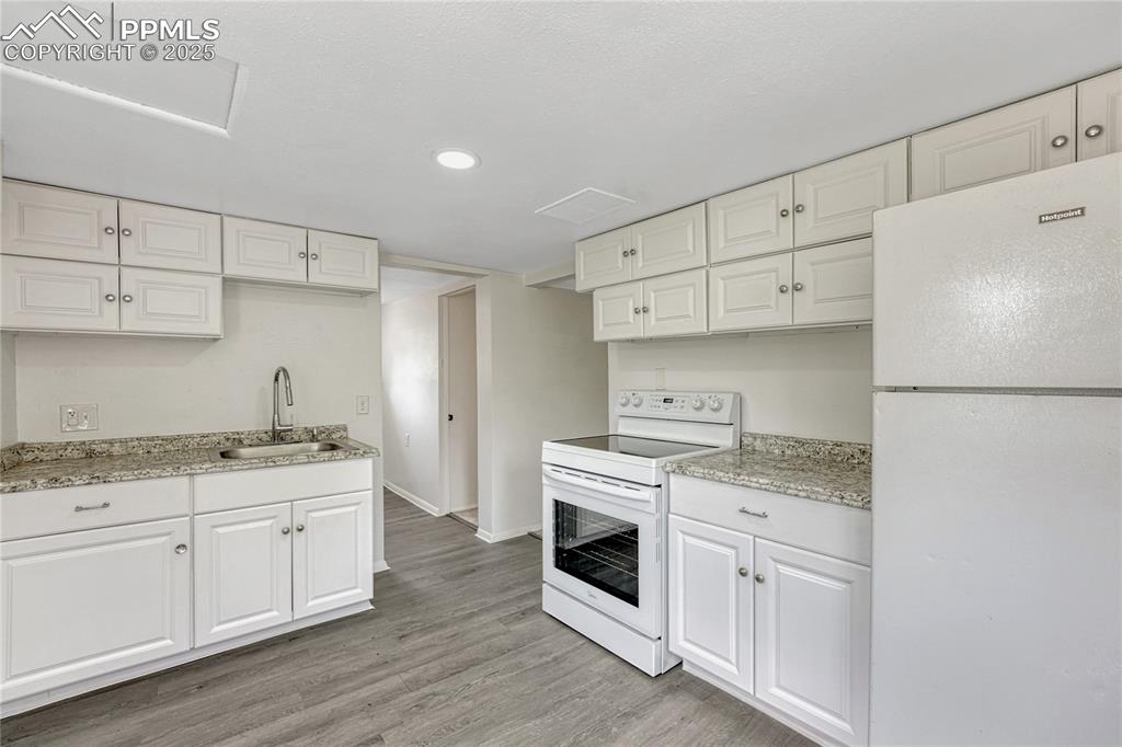 Image 9 of 29: Kitchen with white appliances, light wood-style flooring, white cabinetry, 