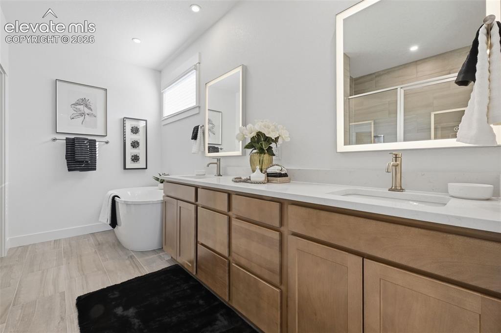 Image 19 of 49: primary bath with double vanity and lit mirrors 
