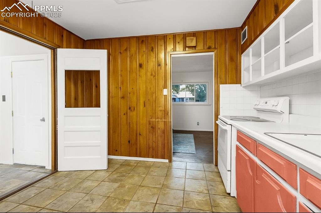 Image 7 of 14: Kitchen with light countertops, white electric range oven, wooden walls, br
