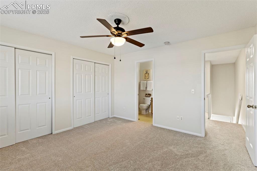 Image 13 of 26: Primary bedroom featuring multiple closets, light colored carpet, a texture