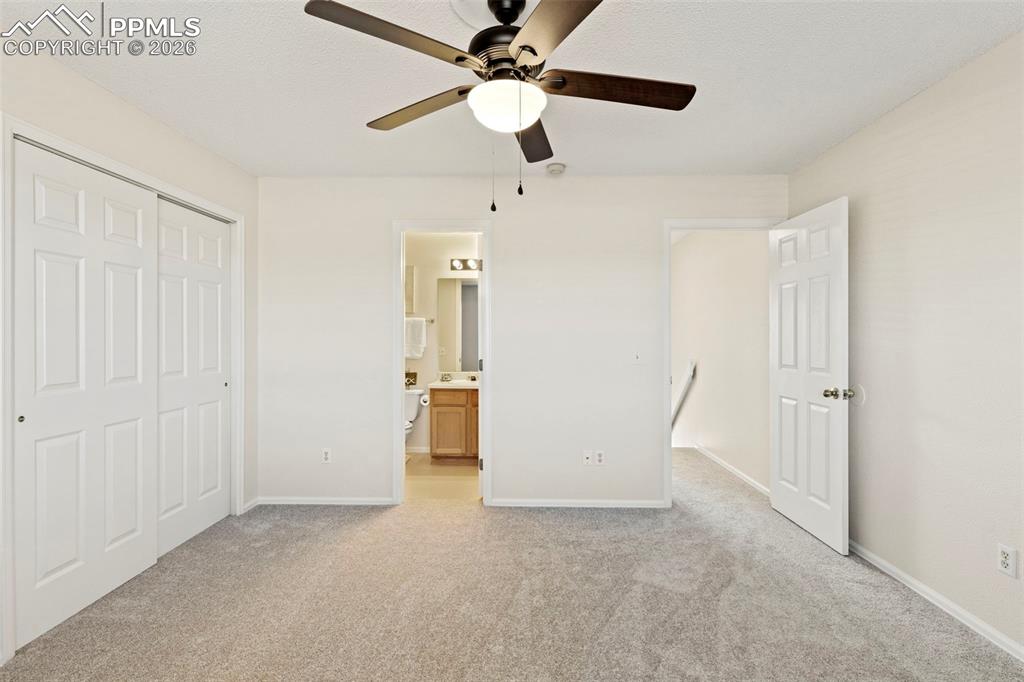 Image 15 of 26: Unfurnished bedroom featuring light carpet, a ceiling fan, a closet, and en
