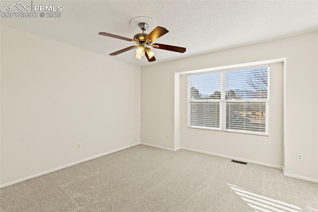 Image 18 of 26: Carpeted empty room with a textured ceiling and ceiling fan