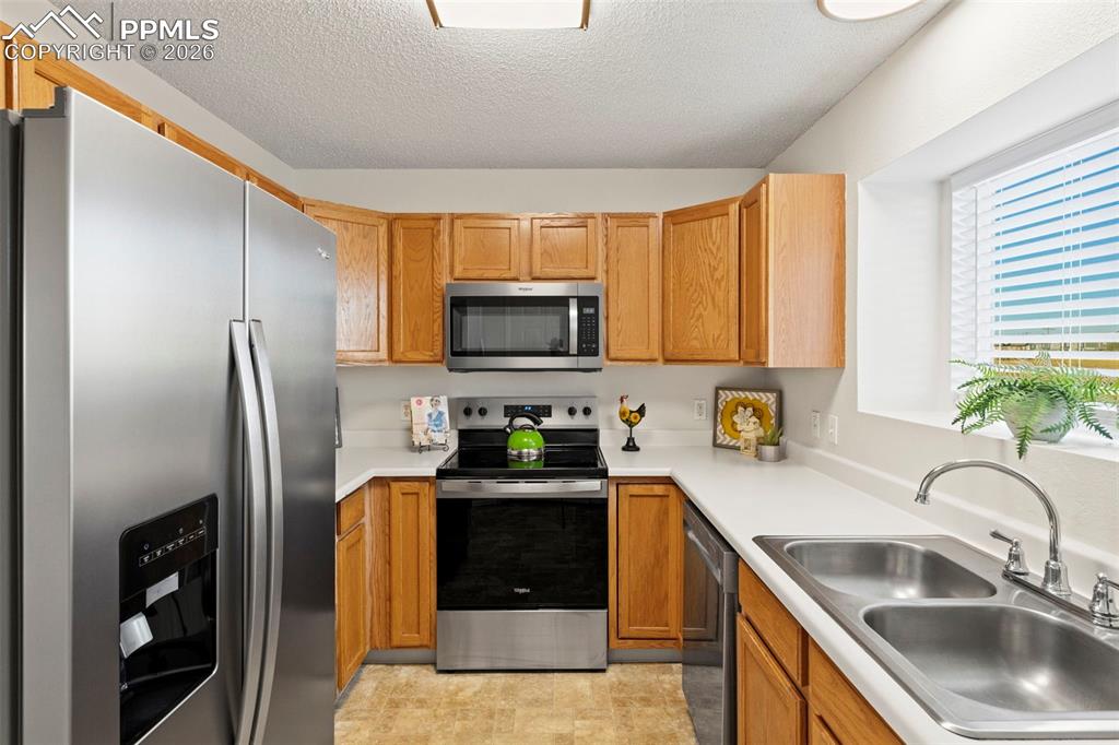 Image 6 of 26: Kitchen with appliances with stainless steel finishes, light countertops, a