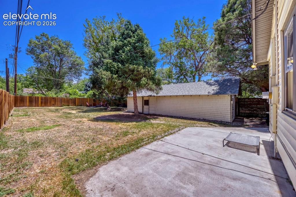 Image 30 of 36: View across the rear patio to the garage and yard area!