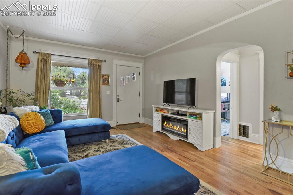 Image 11 of 36: Living room featuring arched walkways, light wood-style flooring, and a gla