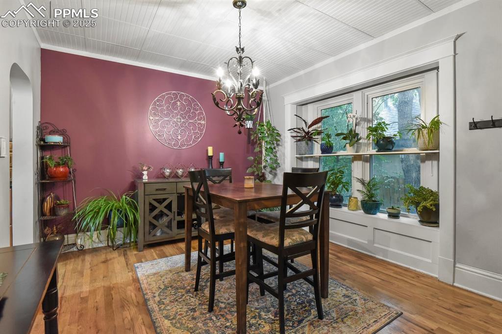 Image 12 of 36: Dining space featuring crown molding, wood finished floors, and arched walk