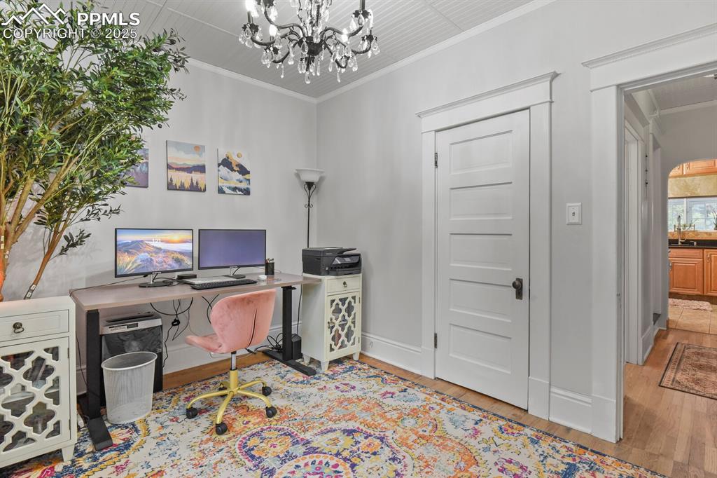Image 15 of 36: Home office with crown molding, a chandelier, and light wood-style floors