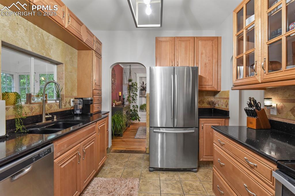 Image 18 of 36: Kitchen featuring stainless steel appliances, decorative backsplash, glass