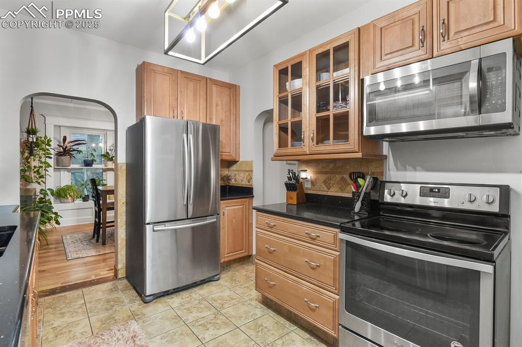 Image 19 of 36: Kitchen featuring appliances with stainless steel finishes, decorative back