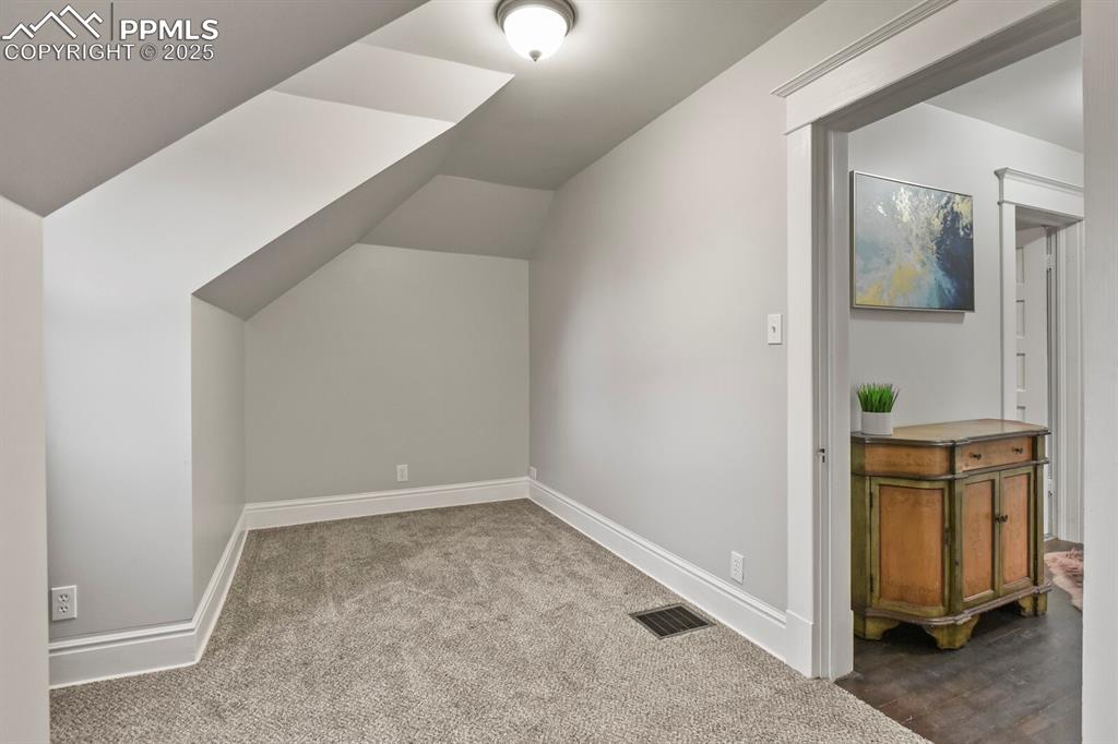 Image 27 of 36: Additional living space featuring vaulted ceiling and carpet