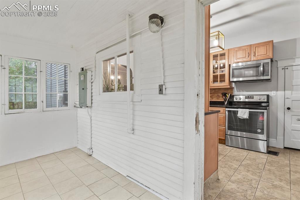 Image 29 of 36: Kitchen with light tile patterned flooring, dark countertops, stainless ste