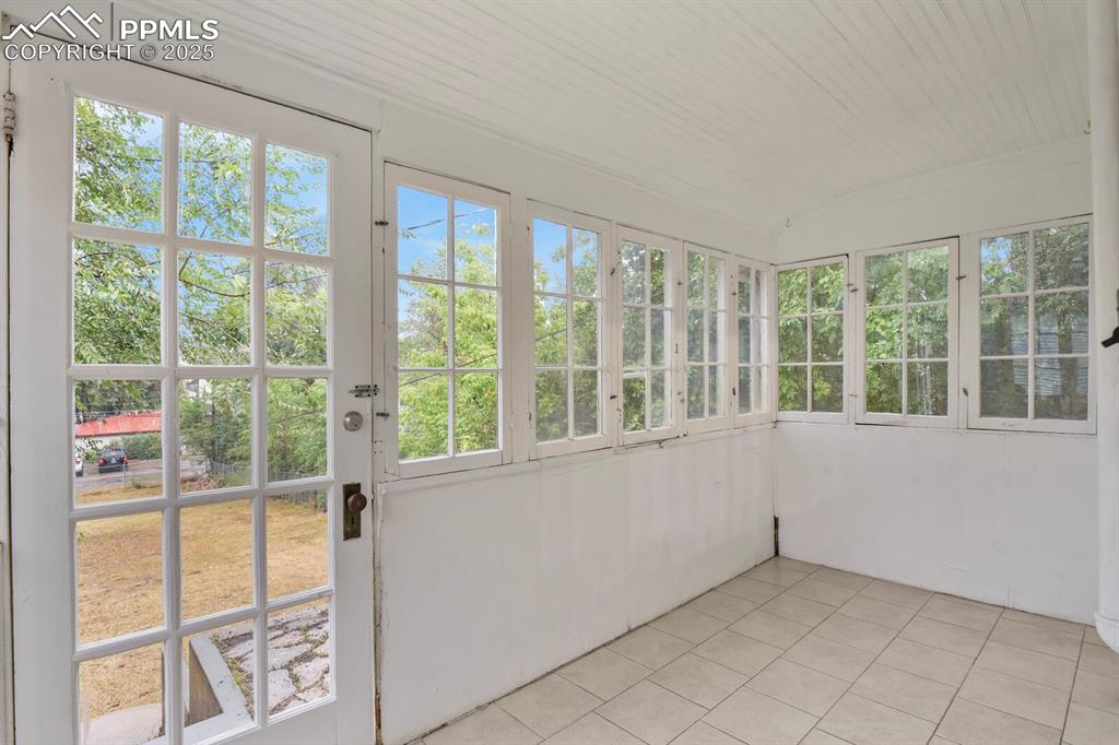 Image 30 of 36: Unfurnished sunroom featuring tile patterned flooring, lofted ceiling, and