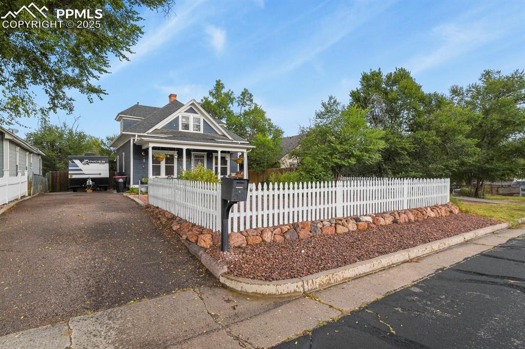 Image 5 of 36: View of front of house with a chimney, driveway, a fenced front yard, and a