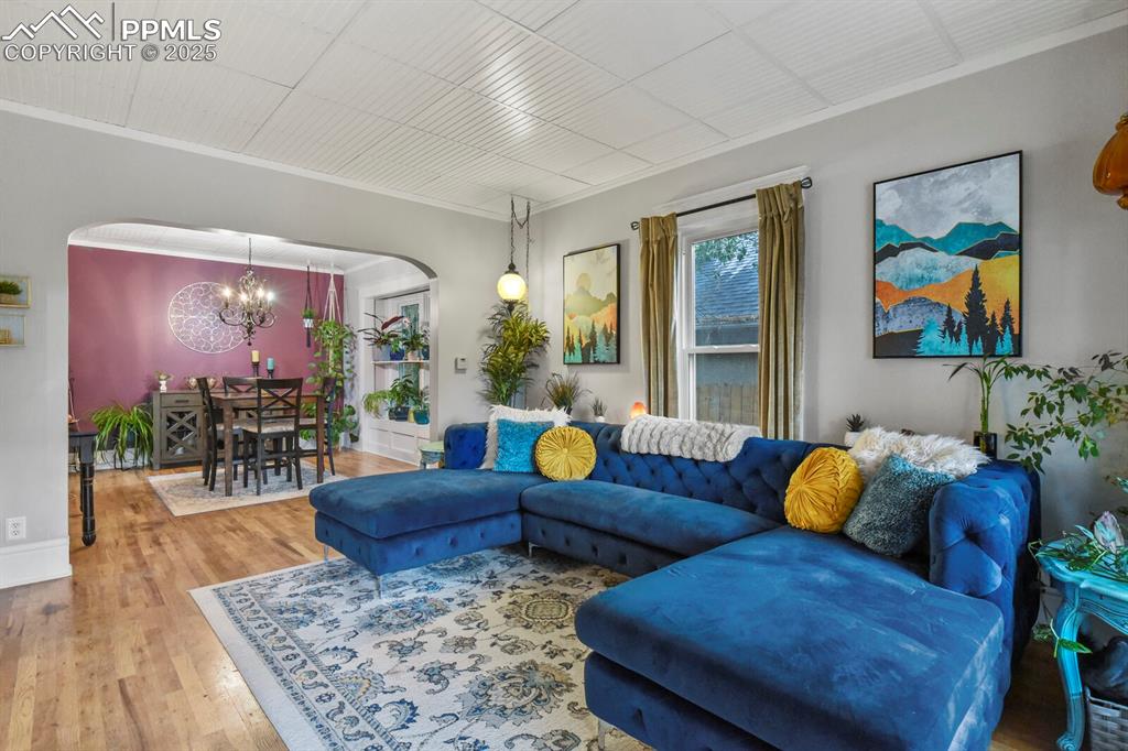 Image 8 of 36: Living area featuring arched walkways, wood finished floors, ornamental mol