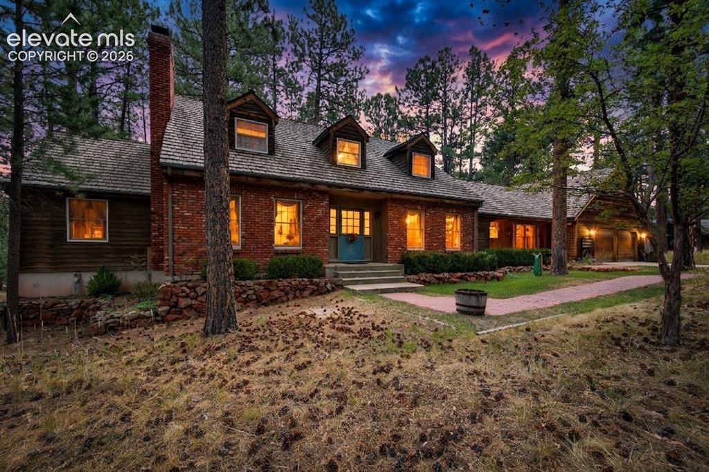 Image 3 of 50: The back of the home glows warmly at twilight, emphasizing the expansive co