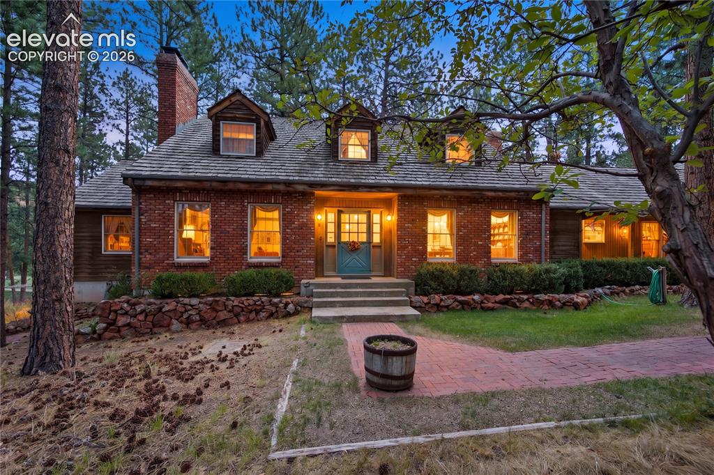 Image 4 of 50: The covered brick porch and outdoor fireplace provide a spectacular setting