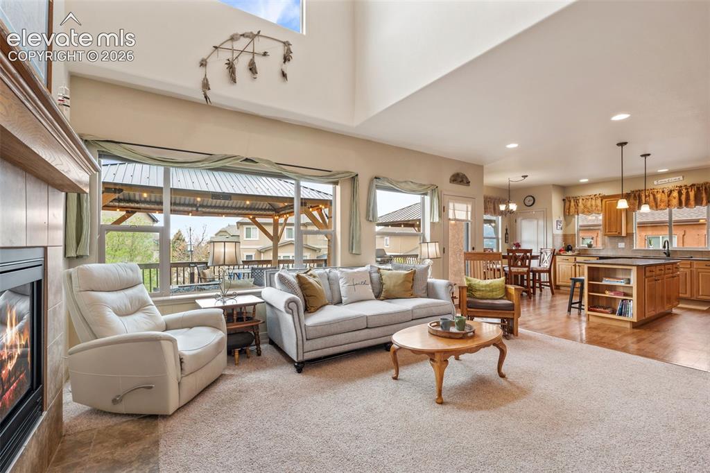 Image 13 of 50: Expansive living area featuring a fireplace with a wood mantle, large windo