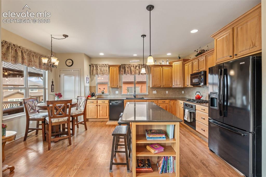 Image 15 of 50: Kitchen featuring wood-finish flooring, natural wood cabinetry, a central i
