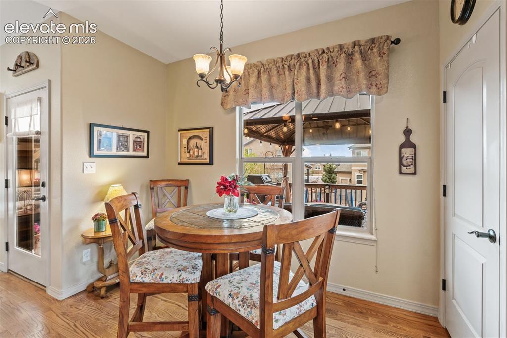 Image 19 of 50: Dining area with wood-finish flooring, a window overlooking an outdoor pati