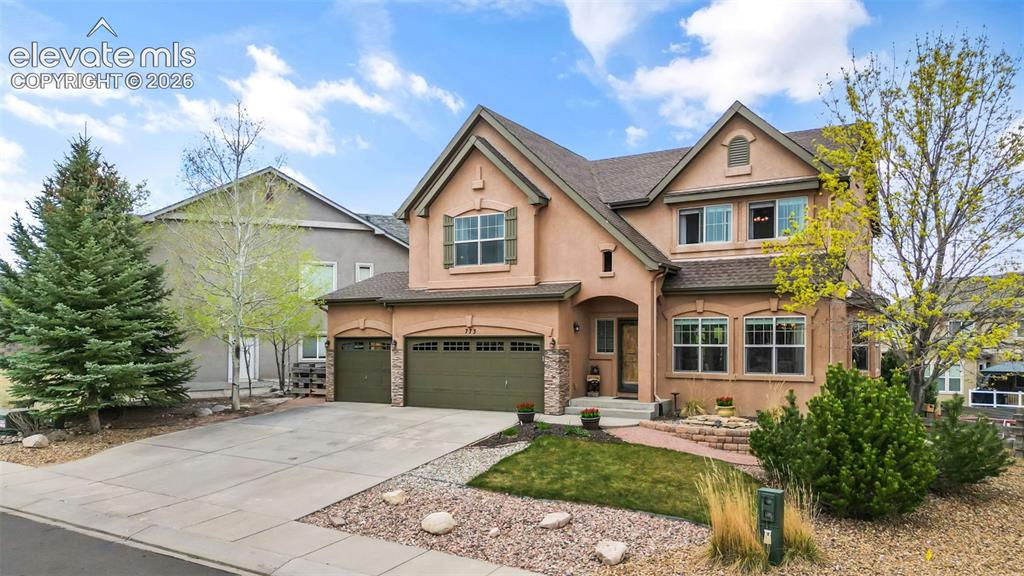 Image 2 of 50: Two-story stucco exterior with stone accents and a three-car garage