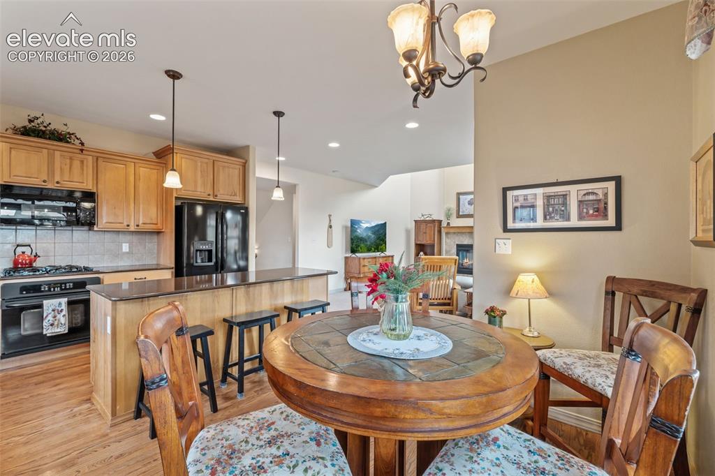 Image 20 of 50: Kitchen featuring wood-finish cabinetry, black appliances, and a tiled back