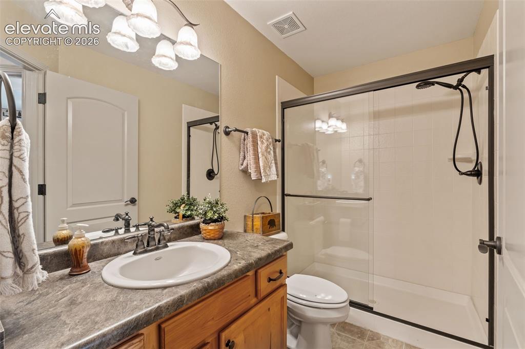 Image 21 of 50: Bathroom featuring a wood-finish vanity with an oval undermount sink, a cou