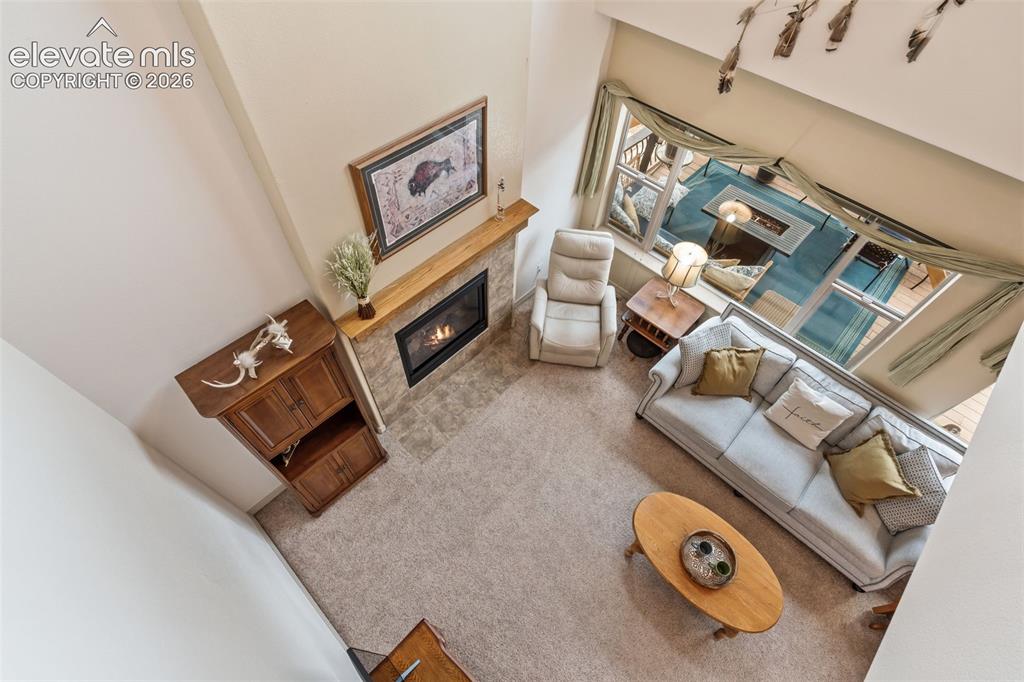 Image 26 of 50: Vaulted living area featuring a stone-faced fireplace with a wood-finish ma