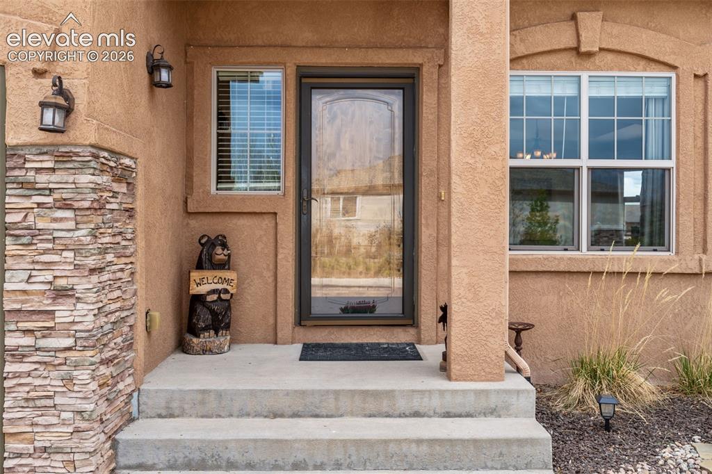Image 3 of 50: Stucco exterior featuring a stone veneer accent column, concrete steps, and