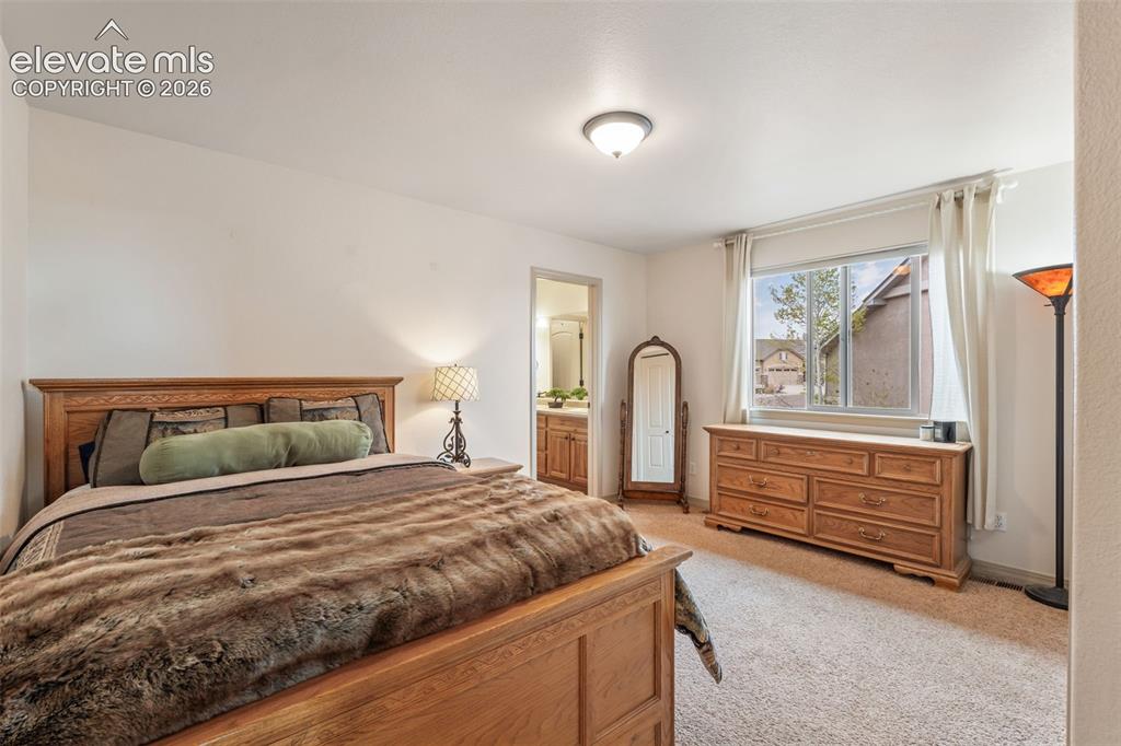 Image 32 of 50: Spacious bedroom featuring light-toned carpeting and a ceiling-mounted ligh