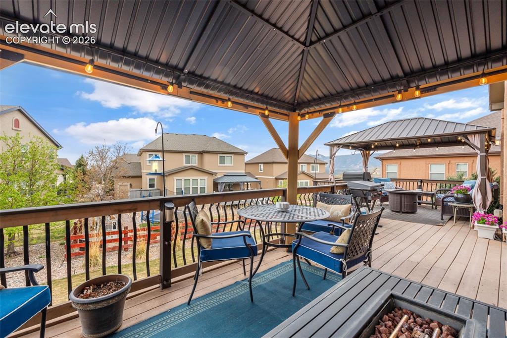 Image 39 of 50: Spacious multi-level deck featuring a primary covered pergola with string l
