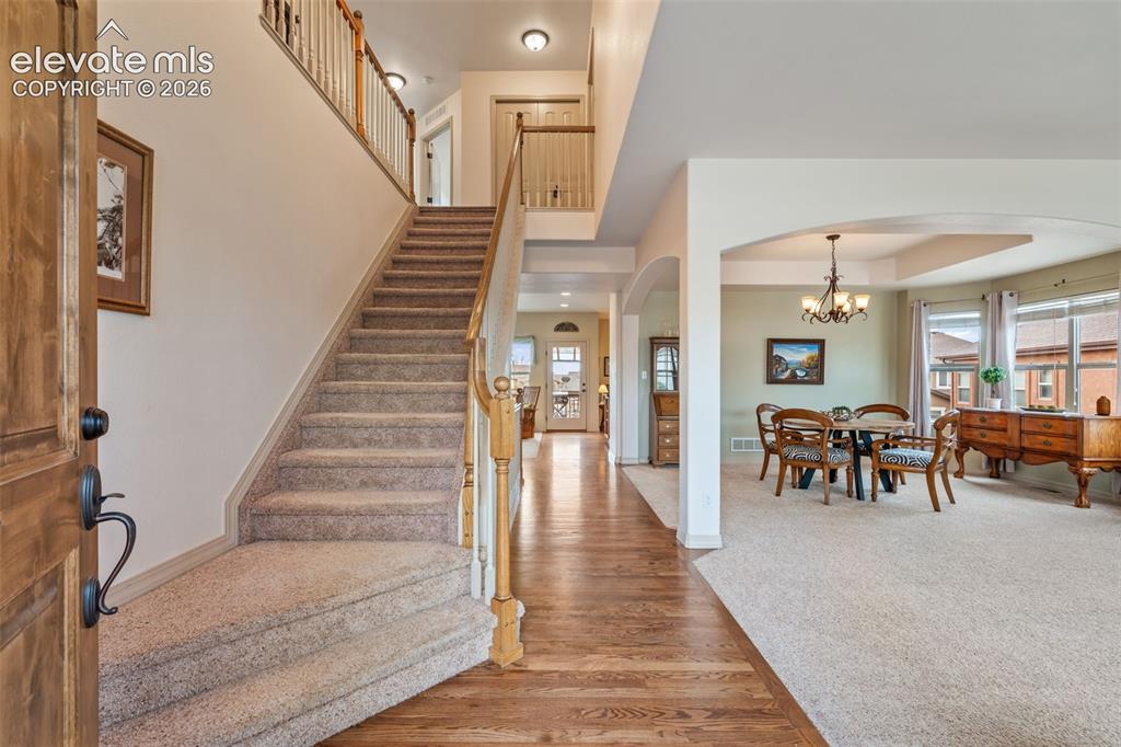 Image 4 of 50: Foyer featuring wood-finish flooring, a carpeted staircase with wood banist