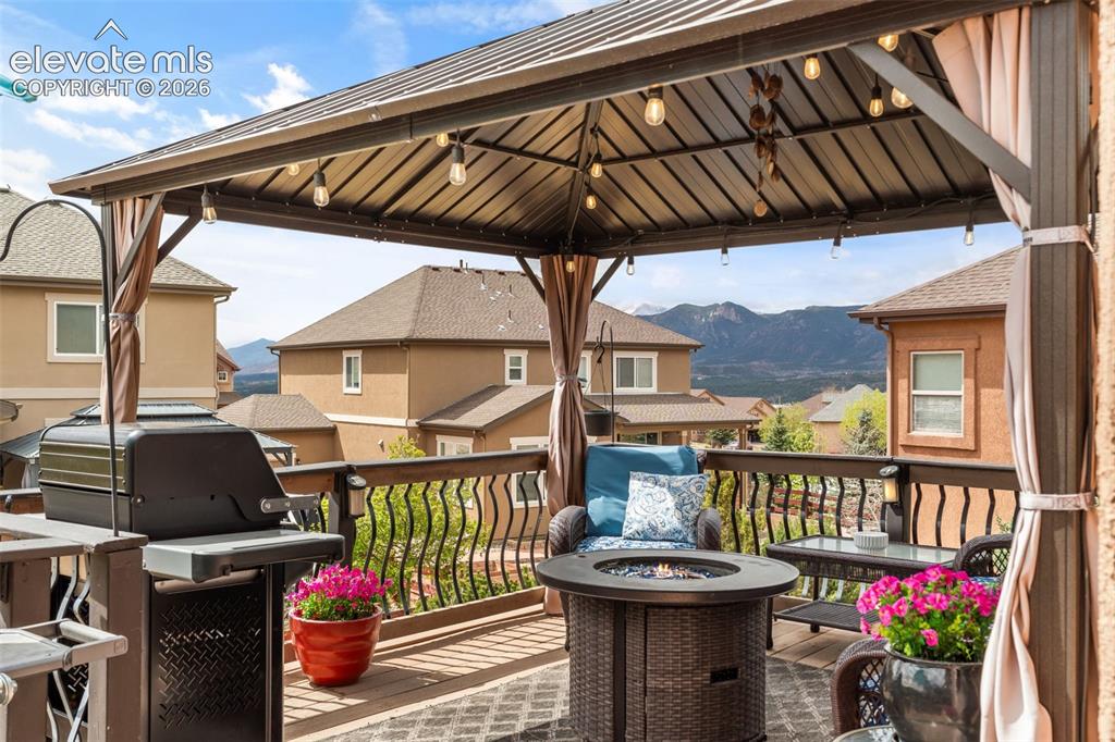 Image 40 of 50: Outdoor deck featuring a metal gazebo with string lighting, a brown wood-fi