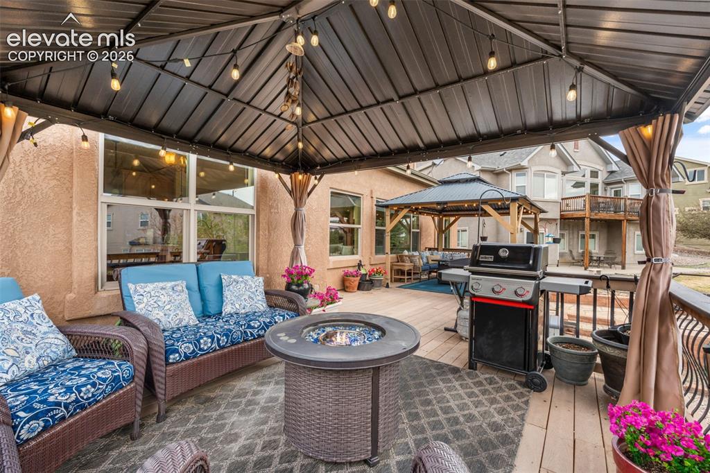Image 41 of 50: Covered patio featuring string lighting, a gas fire pit, and a built-in out