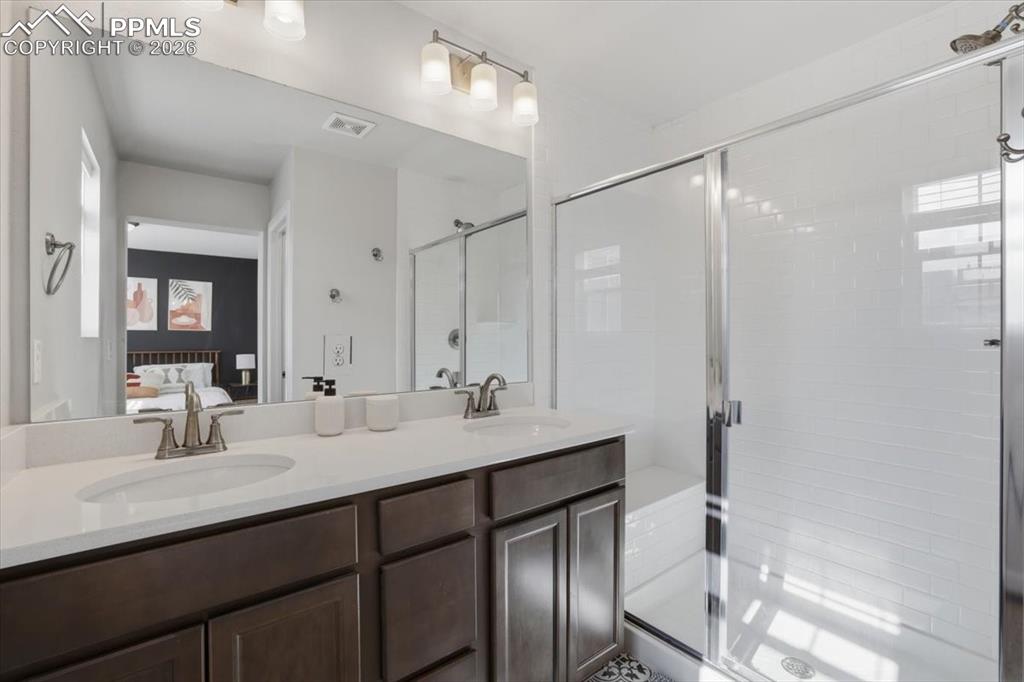 Image 29 of 40: Primary bathroom with dual sinks and walk-in shower.