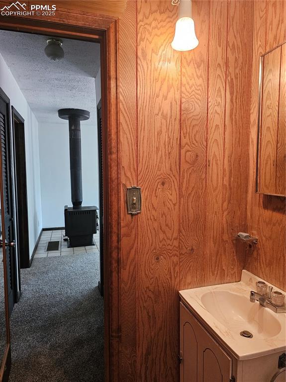 Image 9 of 13: Bathroom with a textured ceiling, vanity, and a wood stove