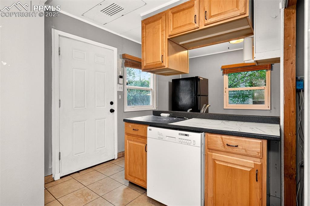Image 4 of 12: Kitchen with dishwasher, light tile patterned floors, freestanding refriger
