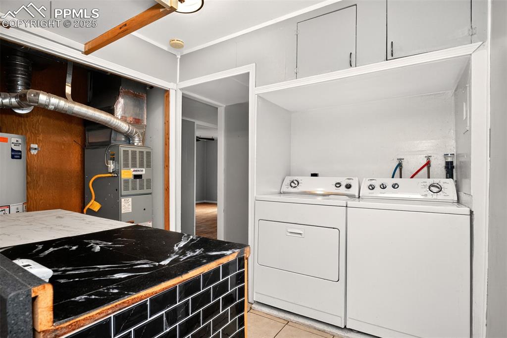 Image 5 of 12: Laundry room with water heater, separate washer and dryer, light tile patte