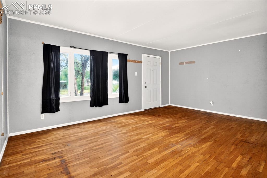 Image 6 of 12: Empty room with wood finished floors and ornamental molding