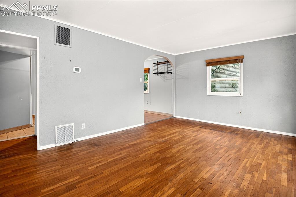 Image 7 of 12: Living room with wood-type flooring, arched walkways, and crown molding