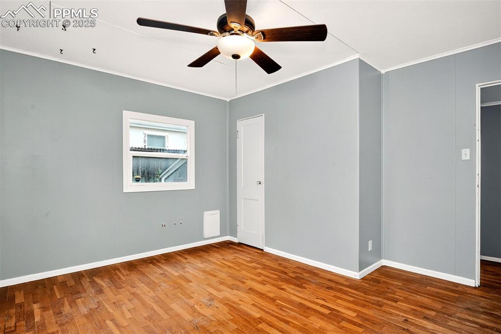 Image 8 of 12: Primary bedroom with wood finished floors, crown molding, and a ceiling fan